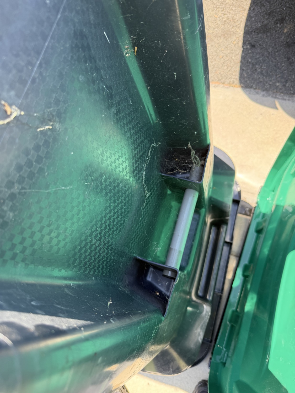 Before: dusty trash bin lid hinge with cobwebs